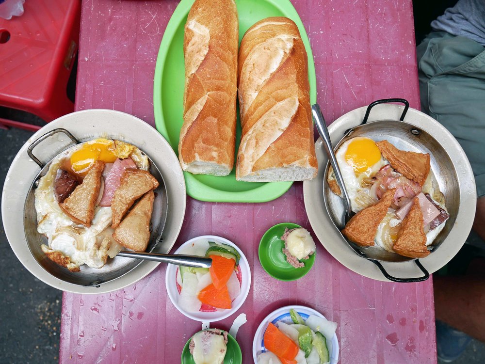  Served with flaky baguettes and pickled vegetables, the still sizzling eggs were topped with pork, onions and tofu. 