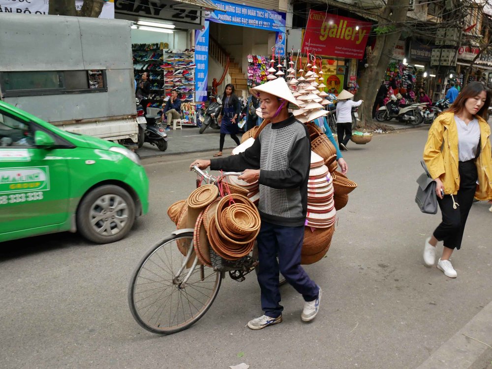  The bike is so overloaded with baskets and hats that he had to sell some before hopping on!&nbsp; 
