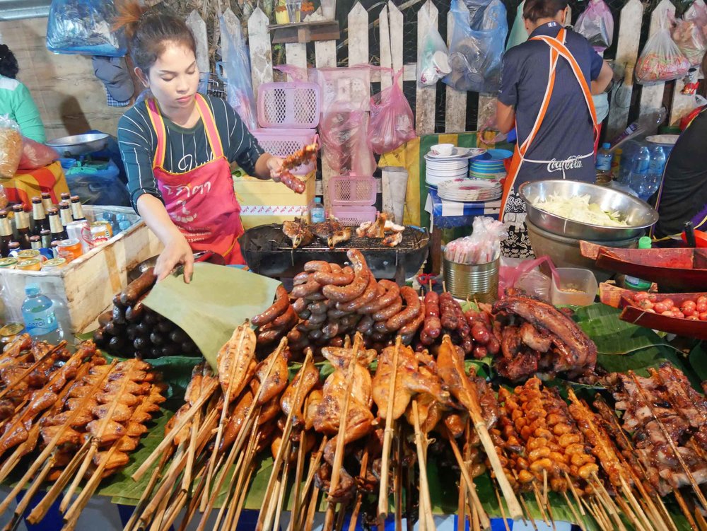  The night market's food district was smoky from the small grills that cooked various meats on long sticks.&nbsp; 