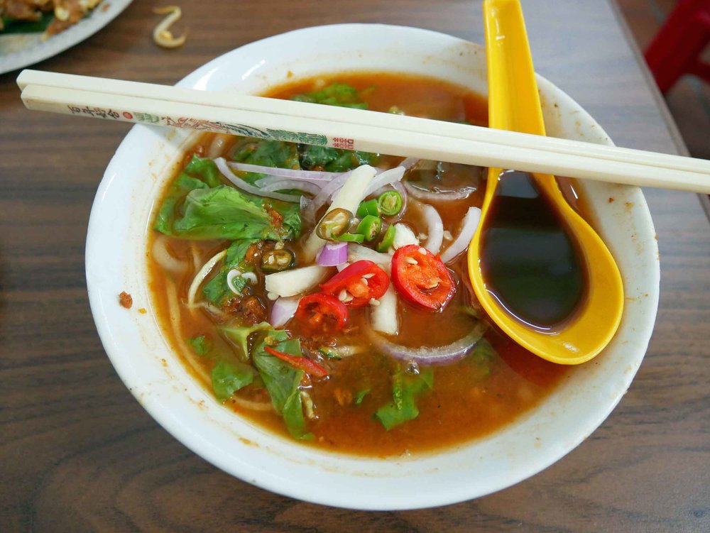  We slurped our way through a bowl of piping hot  laksa , a spicy noodle soup and another specialty.&nbsp; 