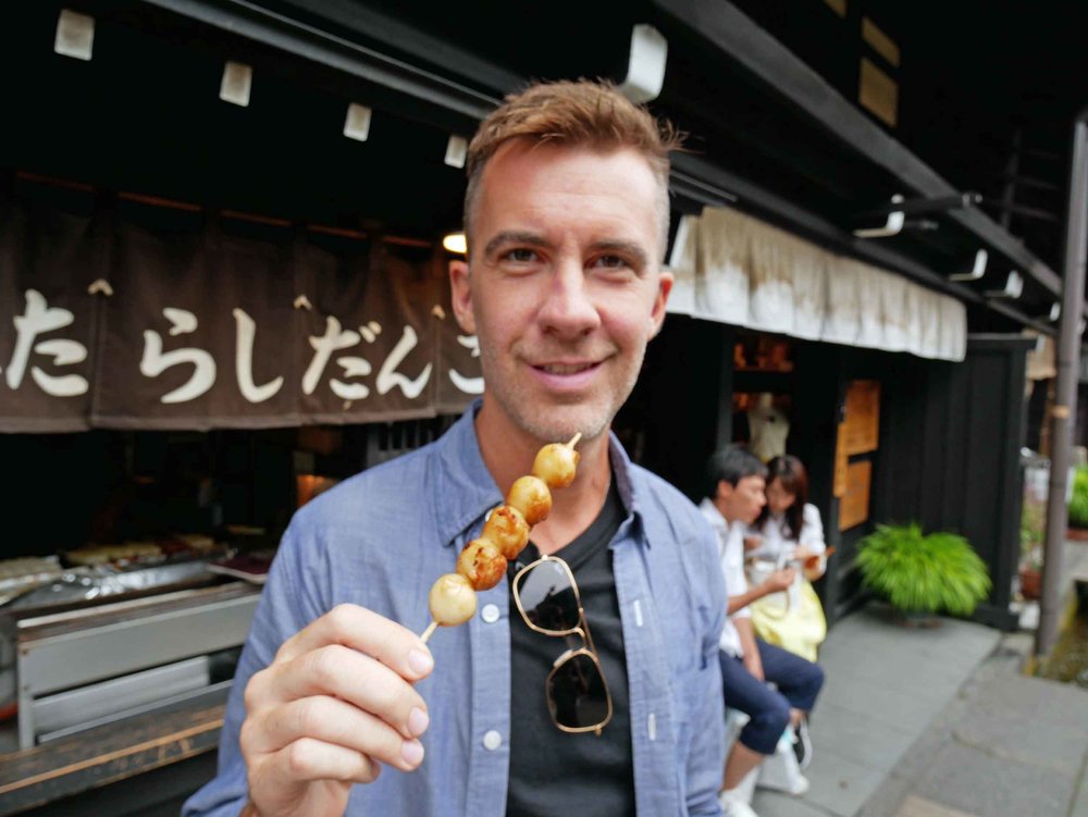  Trey attempts a skewered rice ball with soy sauce, one of the street food eats of Takayama.&nbsp; 