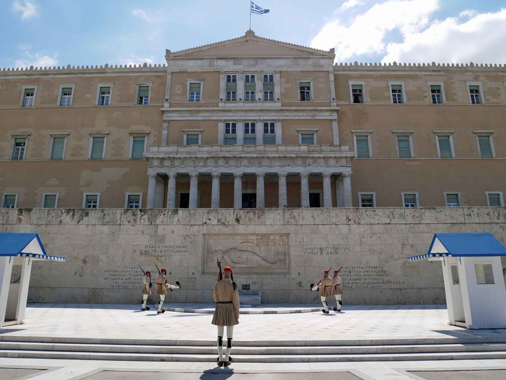  The Changing of the Guard takes place in front of the Hellenic Parliament and Presidential Mansion. &nbsp;The Evzones, or guards,&nbsp;have become symbols of bravery and courage for the Greek people; they also happen to be literal giants. 
