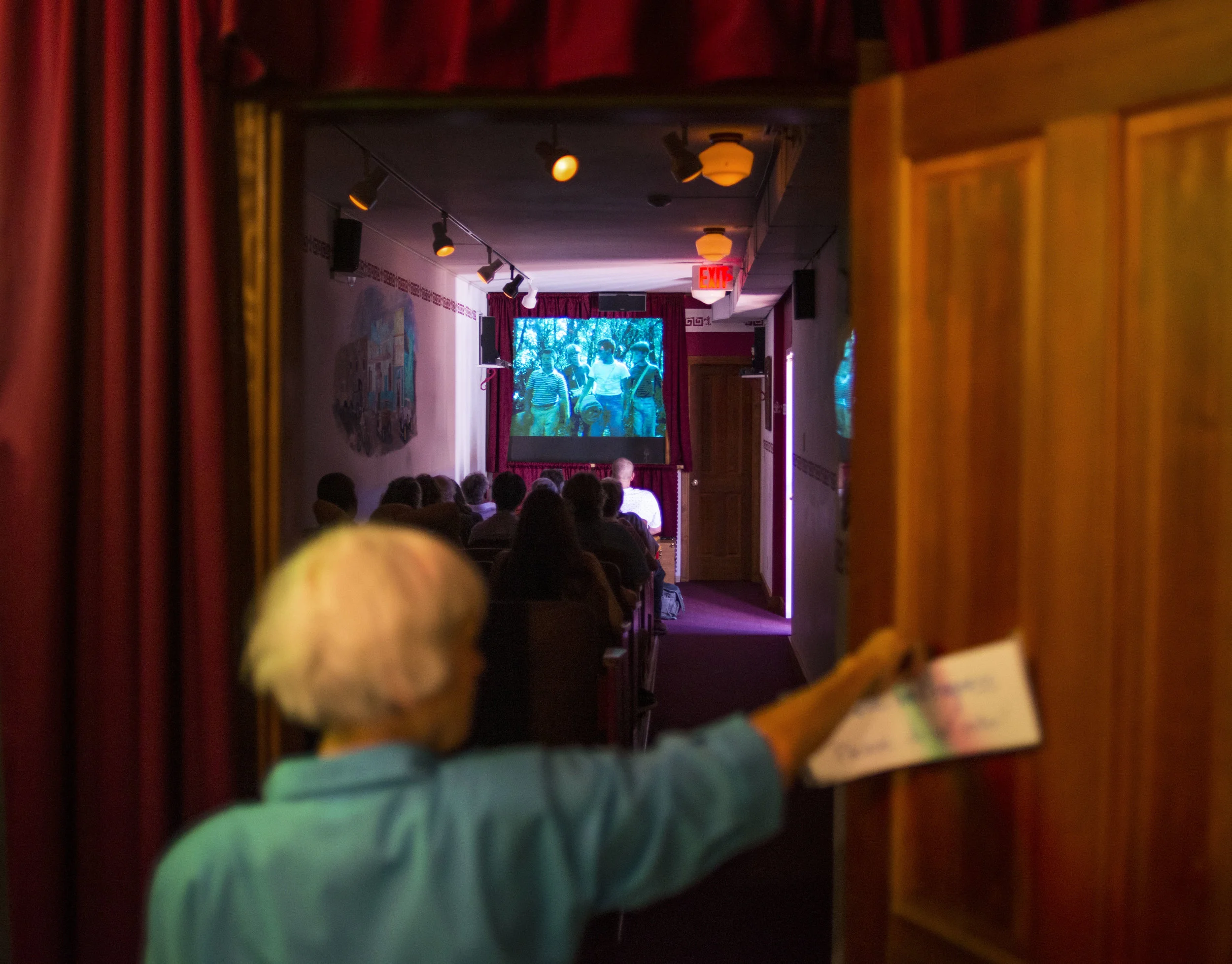  Joni Nelson, a volunteer at the Linn County Historical Museum, hangs a "Movie in Progress" sign on the Boxcar Theatre door as viewers watch a screening of Stand By Me on Sunday afternoon. Stand By Me Day, July 23rd, is an official day in the town of