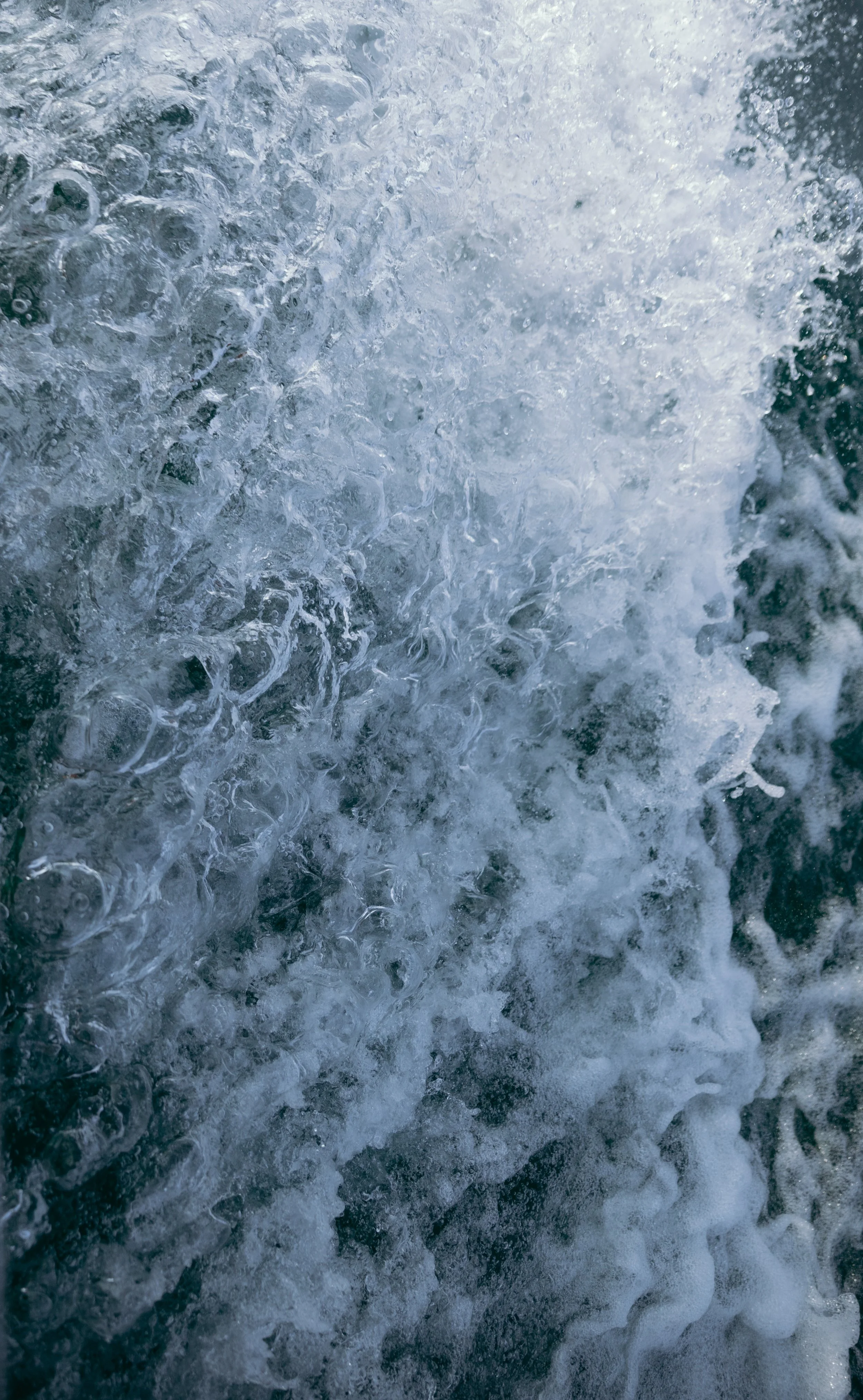 Close-up of crashing ocean waves with frothy white foam and bubbles.