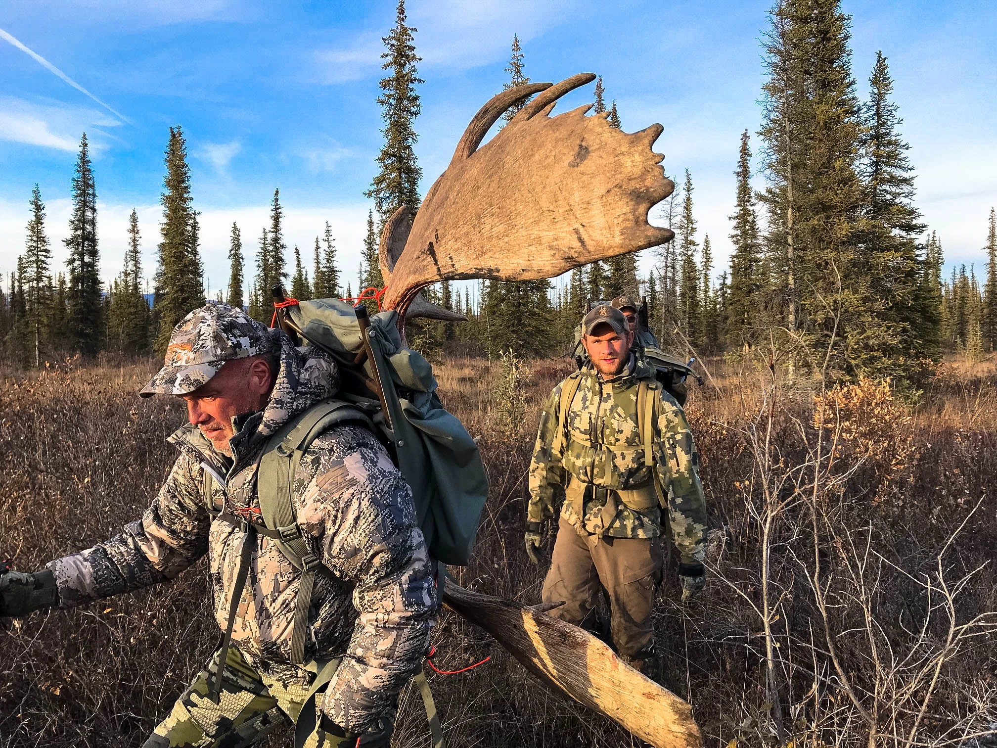 Hunter Chuck packs out his moose antlers while packer Chris follows with a load; Fall 2018