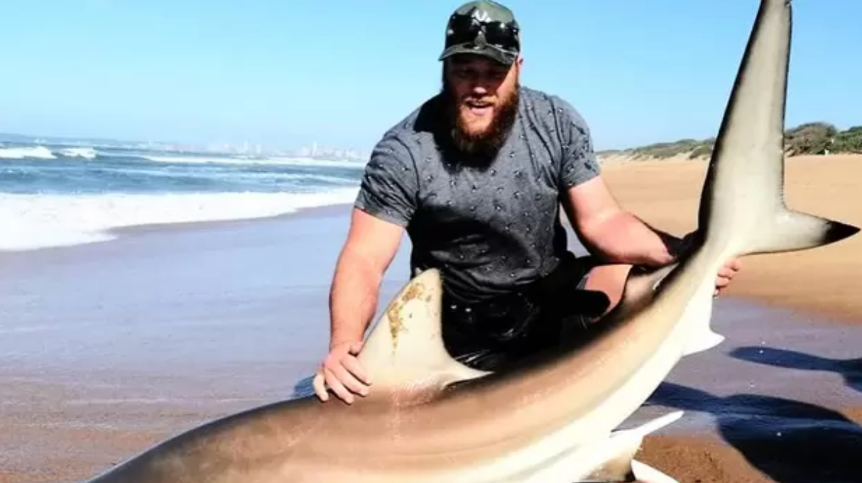 Kyle Cooper with the shark he and his brother helped back into the ocean after it was hooked on his fishing line.
