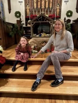 Woman sitting on church steps with a young girl.