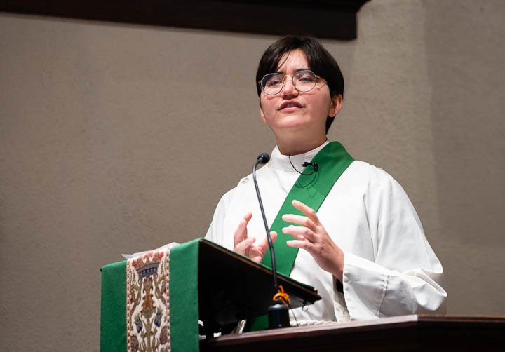A woman preaches from a pulpit.
