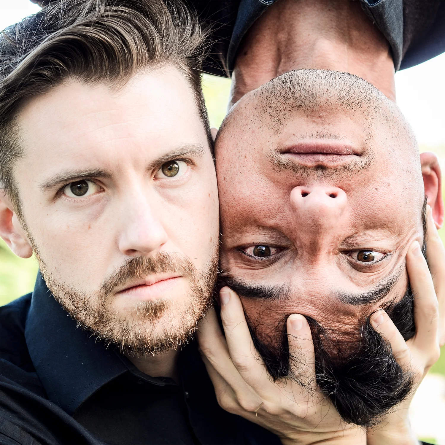 Close-up photo of Chris Ross holding up Travis's upside down head.