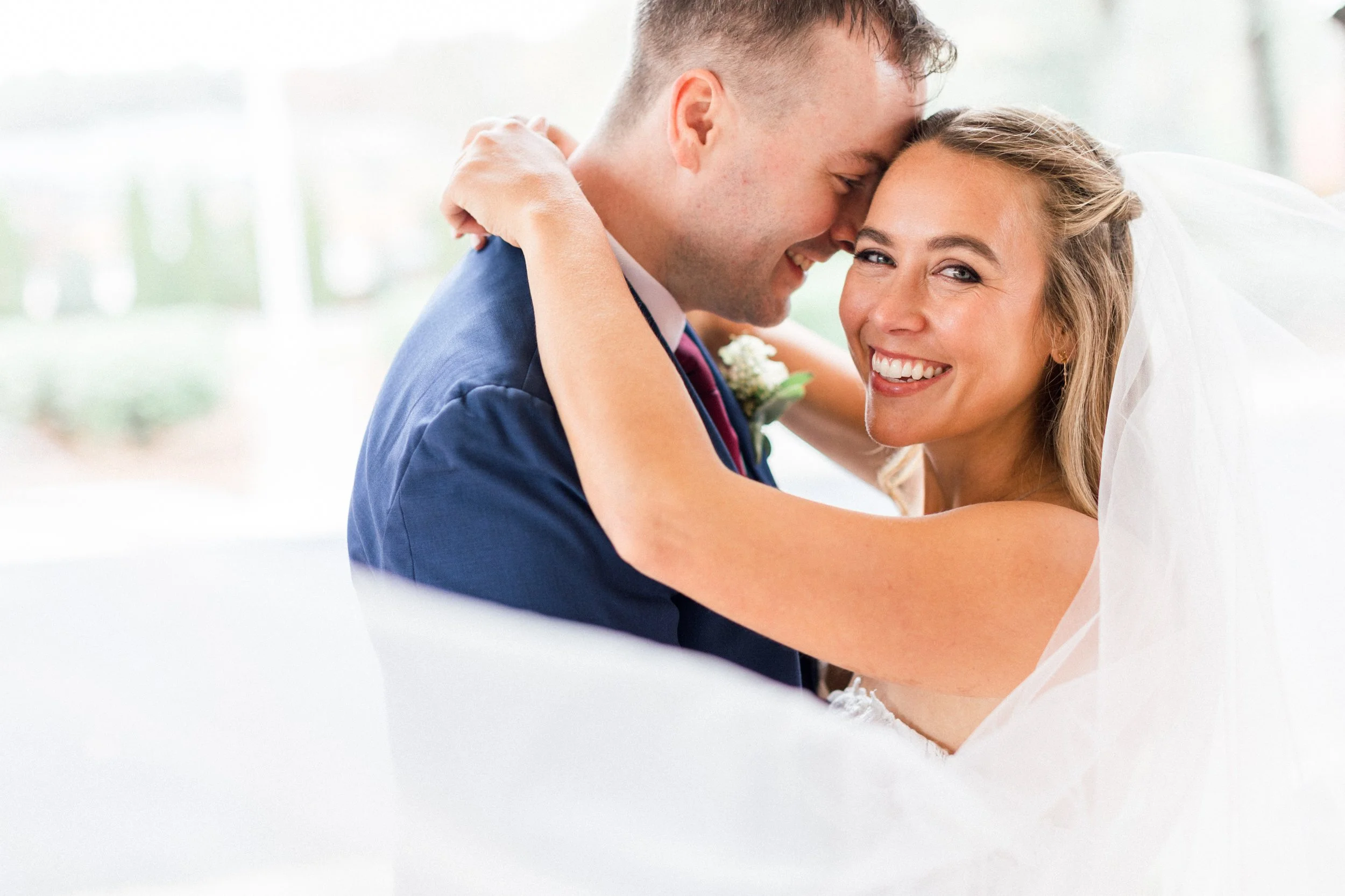 A bride and groom embrace and smile during their wedding ceremony.