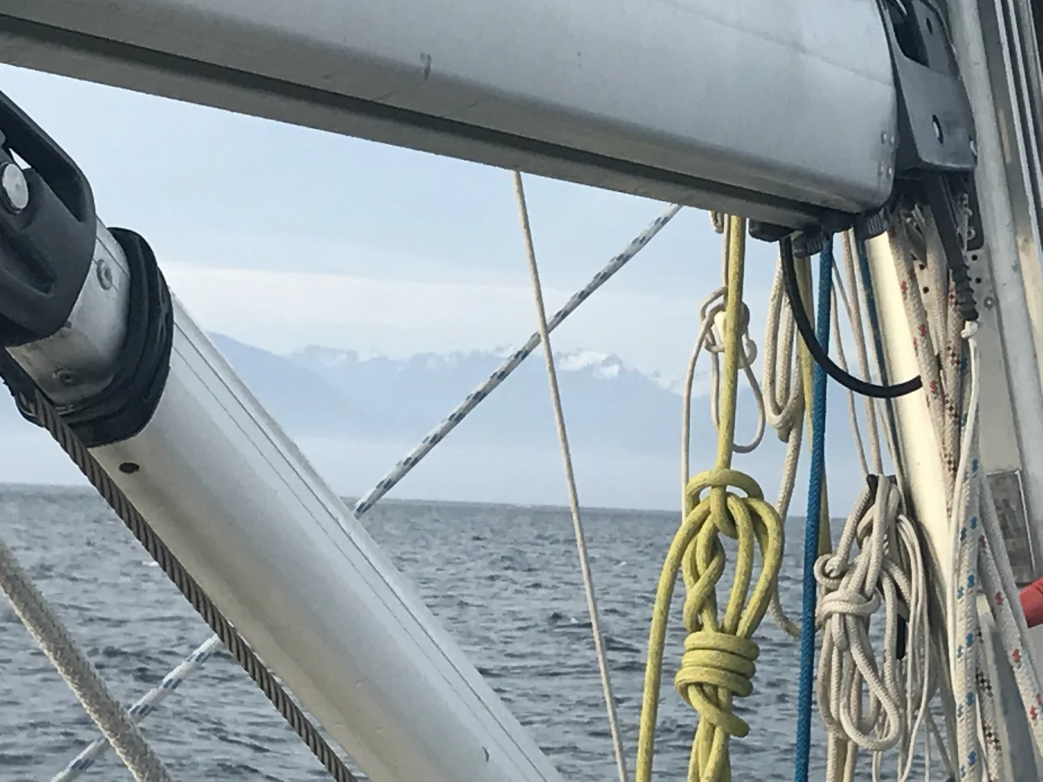 A sail and mountains seen from the deck of a yacht