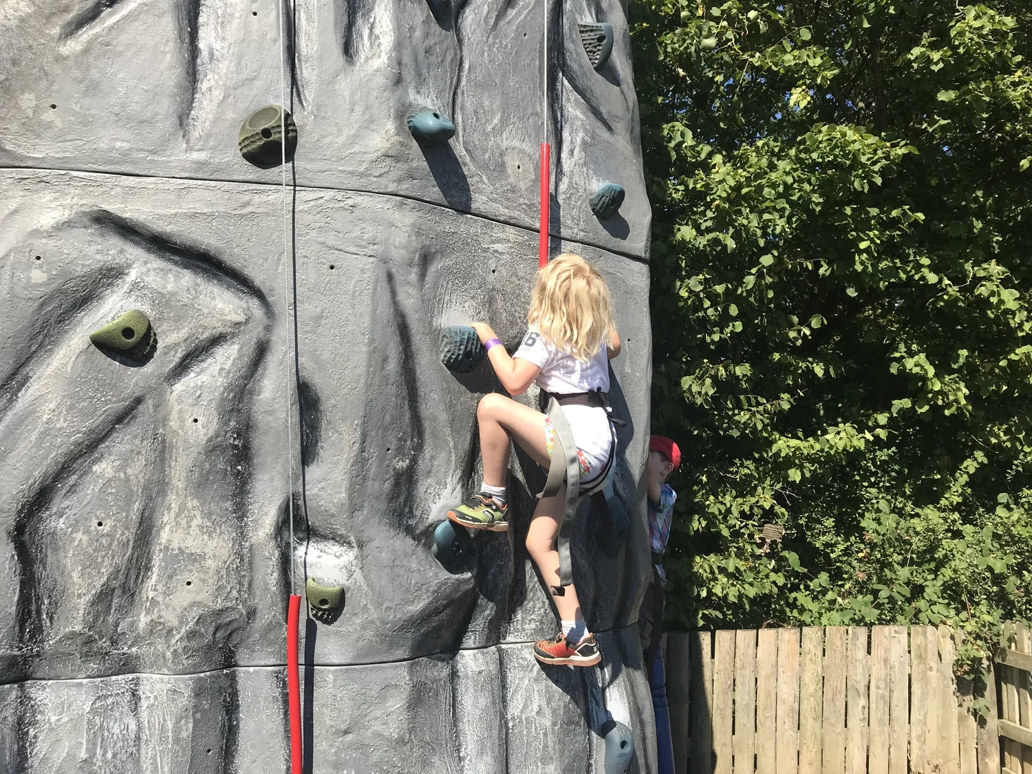 A young climber reaching for the next hold on a climbing wall