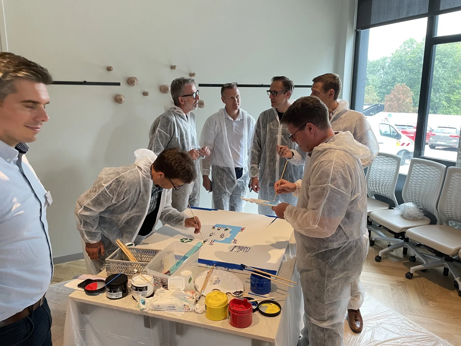 Leaders in overalls painting a shared picture together at an offsite