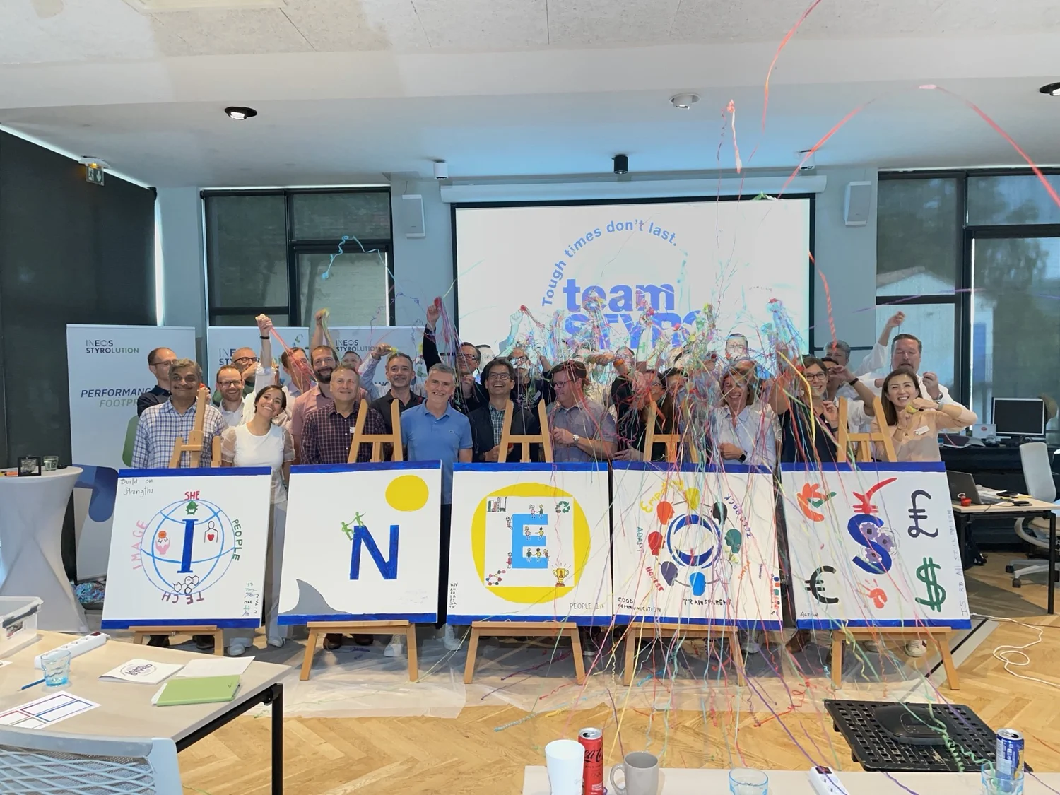 A leadership team celebrating together in front of the paintings they made as a team