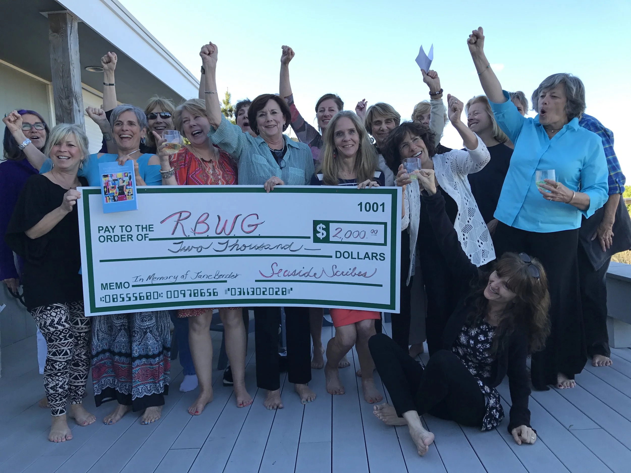 This was taken on May 15, 2017 at the celebration of the launch of The Divine Feminine: An Anthology of Seaside Scribes at the Marten's family beach house in Bethany, following the performance readings by the authors at the Ocean City Center for the Arts. The authors are shown presenting the first round of profits from the sale of the anthology to Maribeth Fischer, Executive Director of the Rehoboth Beach Writers' Guild. The funds went to provide writing scholarships to women in memory of Jane Bender a former member of the Guild who loved poetry and used writing to express her emotions, humor, and insights through during her long journey fighting cancer. Jane's poem along with a trilogy written by her dear friend Margaret Kirby was published posthumously in the anthology. Photograph by Joe Comorat, husband of Gail Comorat, a poet and author in the Anthology. Other proceeds went to Little Pink Houses of Hope, an organization that provides respite and vacations to women under treatment for breast cancer to enjoy creative arts projects at the Art League of Ocean City, Center for the Arts led by Rina Thaler.