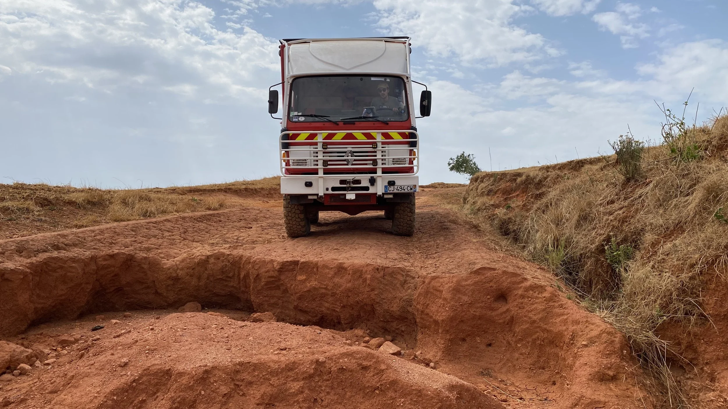 Le RedTruck arrêté devant un énorme trou sur une piste au Nigeria, photo d’aventure en Afrique lors d’une traversée du continent en camion 4x4.