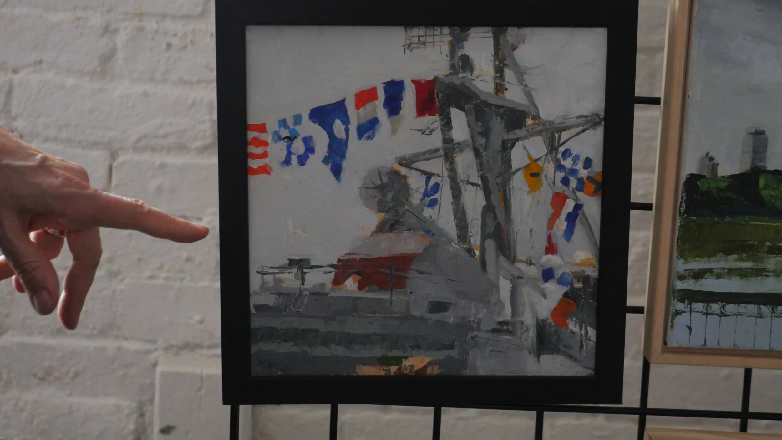  Carol's hand points to a painting of Charlestown's Navy Yard, a project commissioned for a special, commemorative event at the location. 