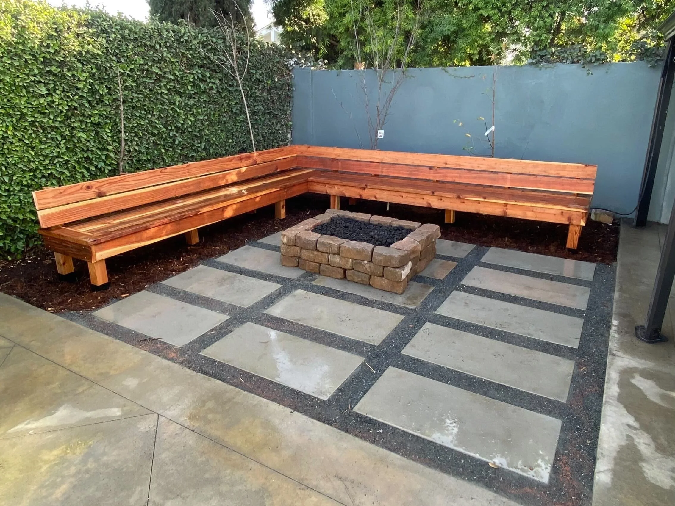 A wrap-around bench made out of beautiful redwood gives this underutilized corner of this backyard new life
