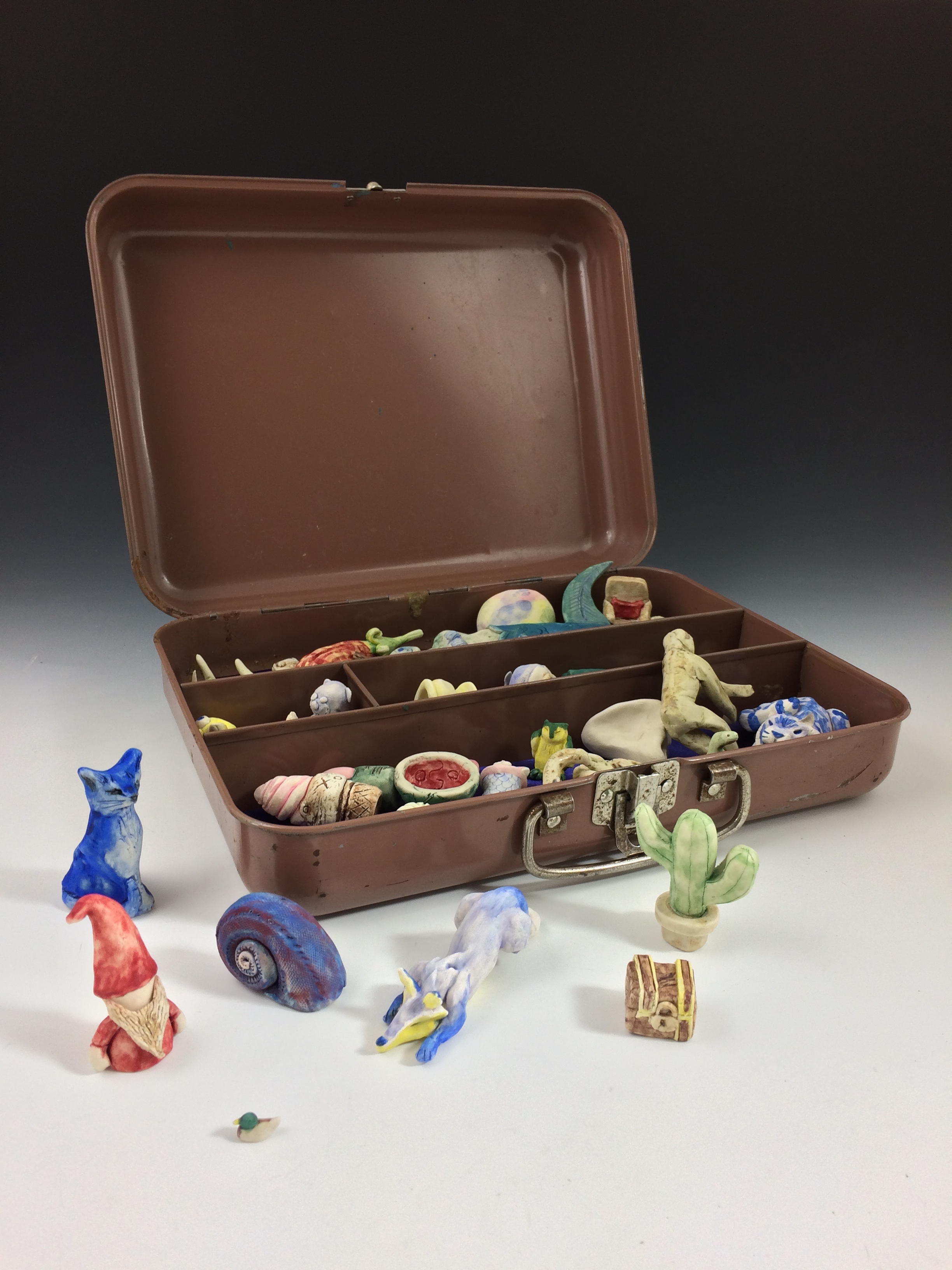 OCTOBER 2016 During fall semester, the Art 203 Introduction to Ceramics class worked collaboratively to make “Managerie”. The piece was donated to a Habitat for Humanity Art Auction fundraiser. The toolbox originated from a Habitat for Humanity Restore, and was repurposed to hold a humorous assortment of miniature porcelain sculptures. 