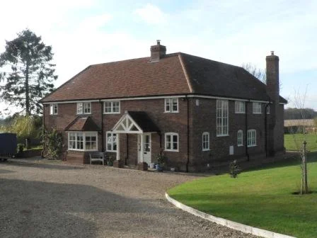 The gravel driveway leads directly down to the front entrance for guest parking, but otherwise forks away from the house to a large garage block with a home office.