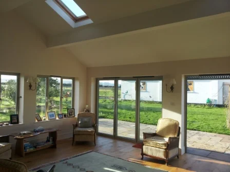 Interior view of new garden room extension to Wiltshire house incorporating log-burner, rooflights and sliding folding doors.