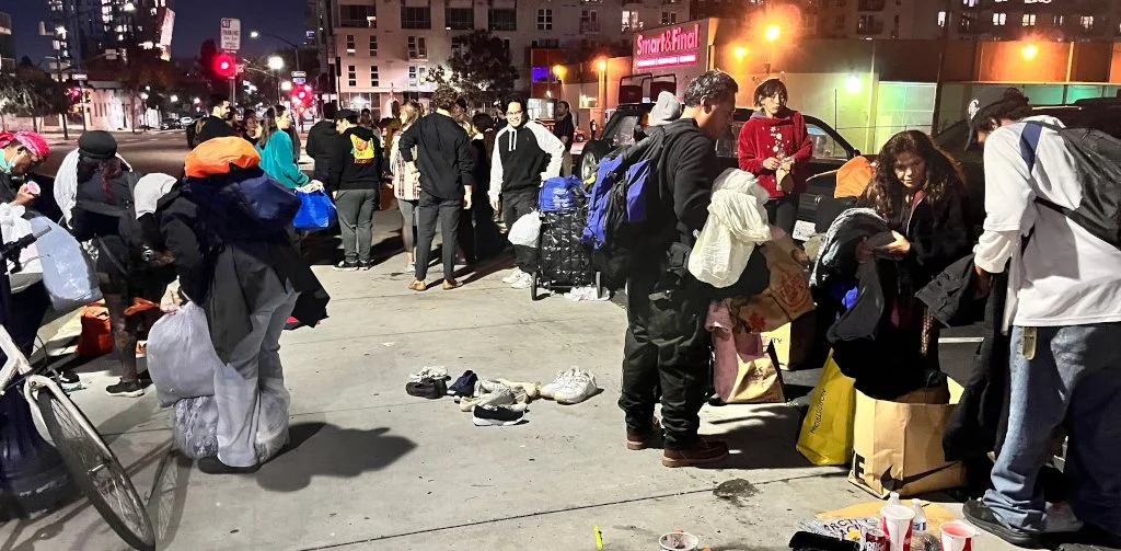 People out on the sidewalk grabbing donated clothing
