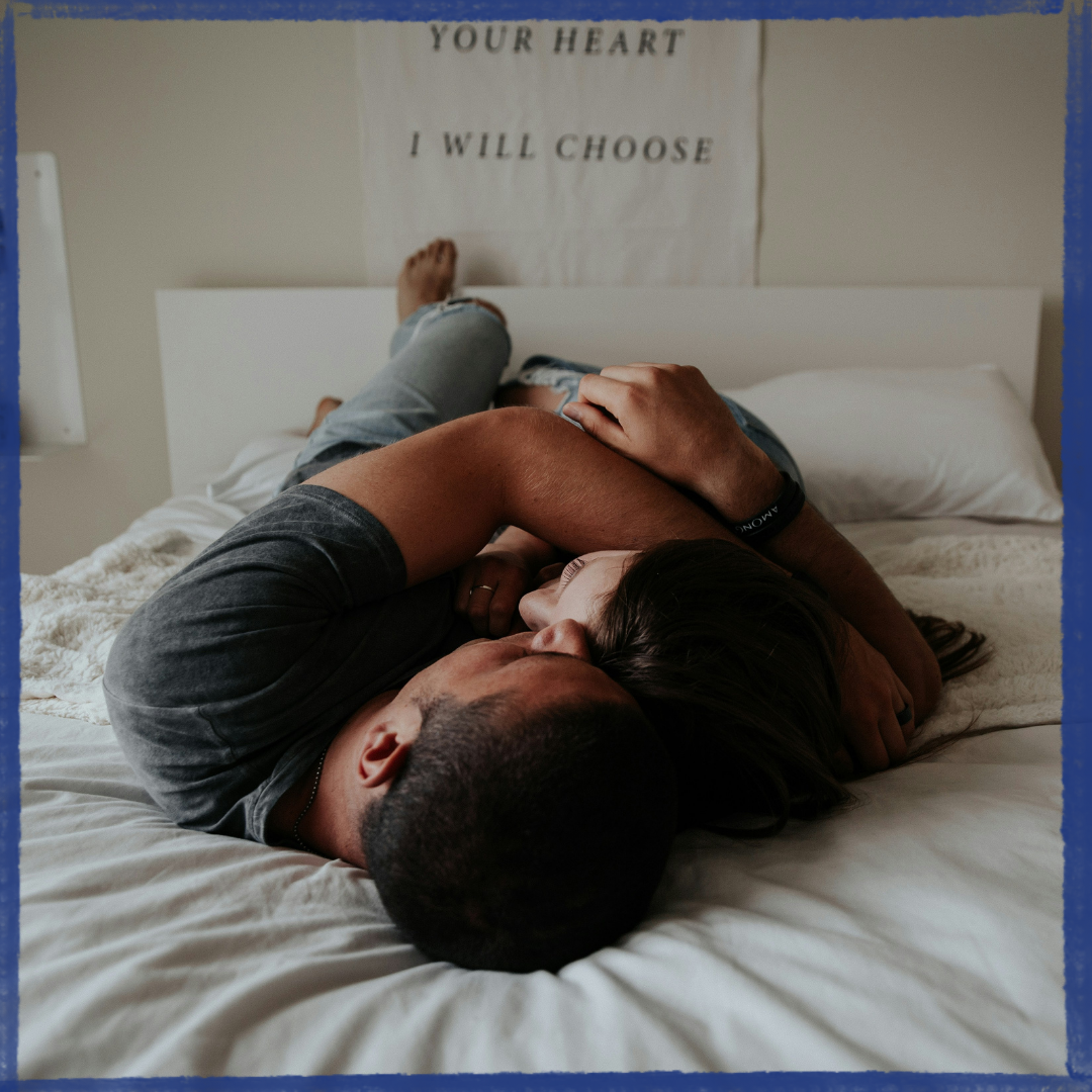 Boy and girl hugging on bed.