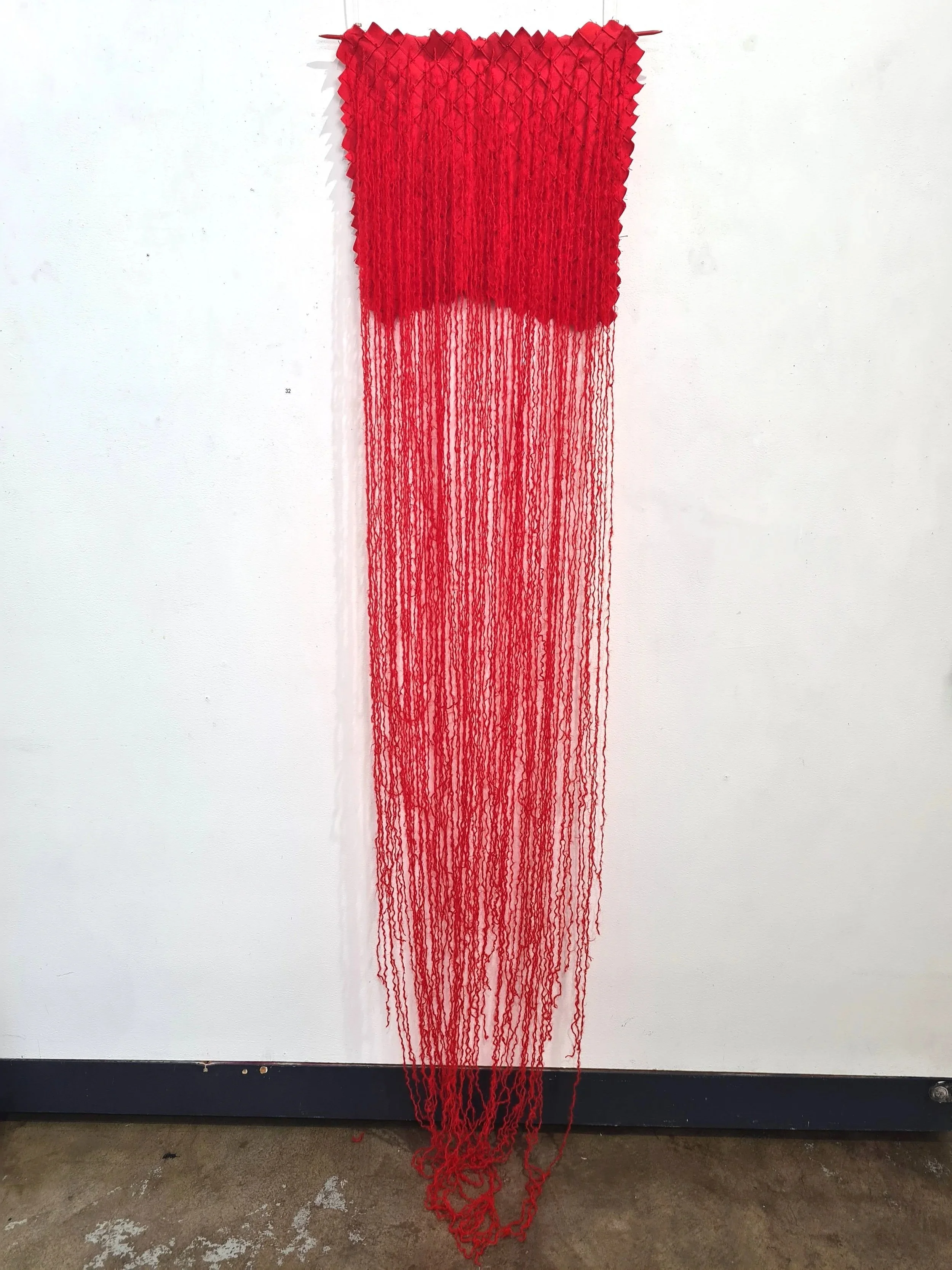 Tethered, 2025-26, discarded wool flannel, found beads and wool on knitting needles