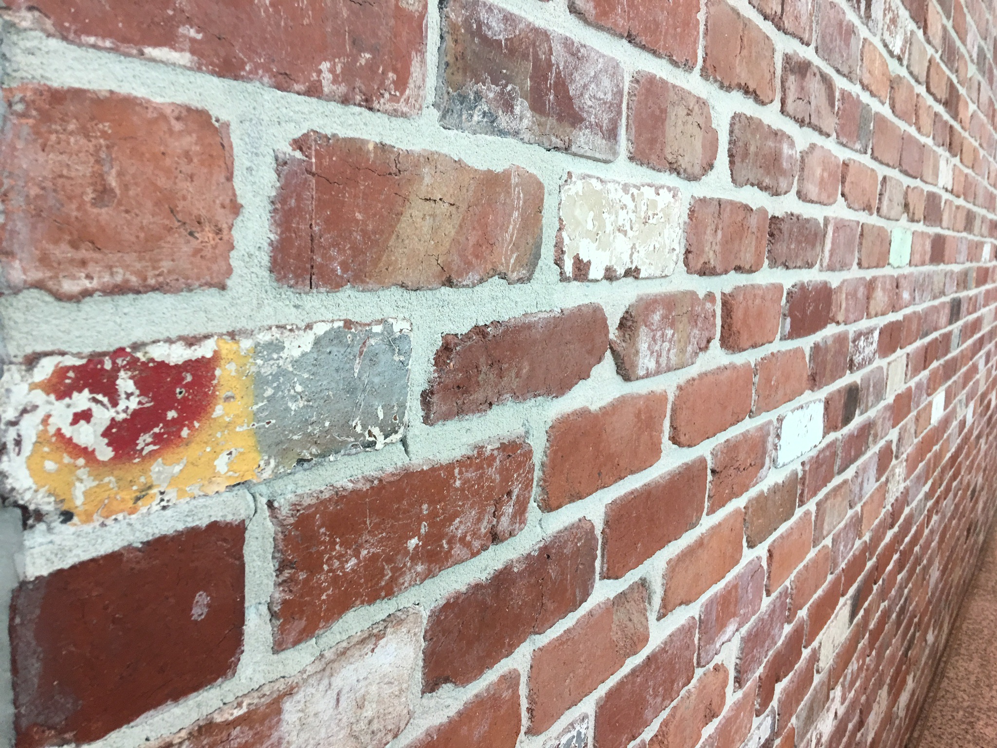 A wall built with reclaimed bricks - an example of a recycled building material.