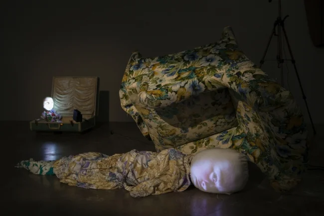 Tony Oursler. Hard Case, 1995. Cloth figure, stuffed chair, video projection, performance by Tracey Leipold. Magasin III Production. Photo: Christian SaltaTony Oursler. Hard Case, 1995. Cloth figure, stuffed chair, video projection, performance by Tracey Leipold. Magasin III Production. Photo: Christian Saltas.