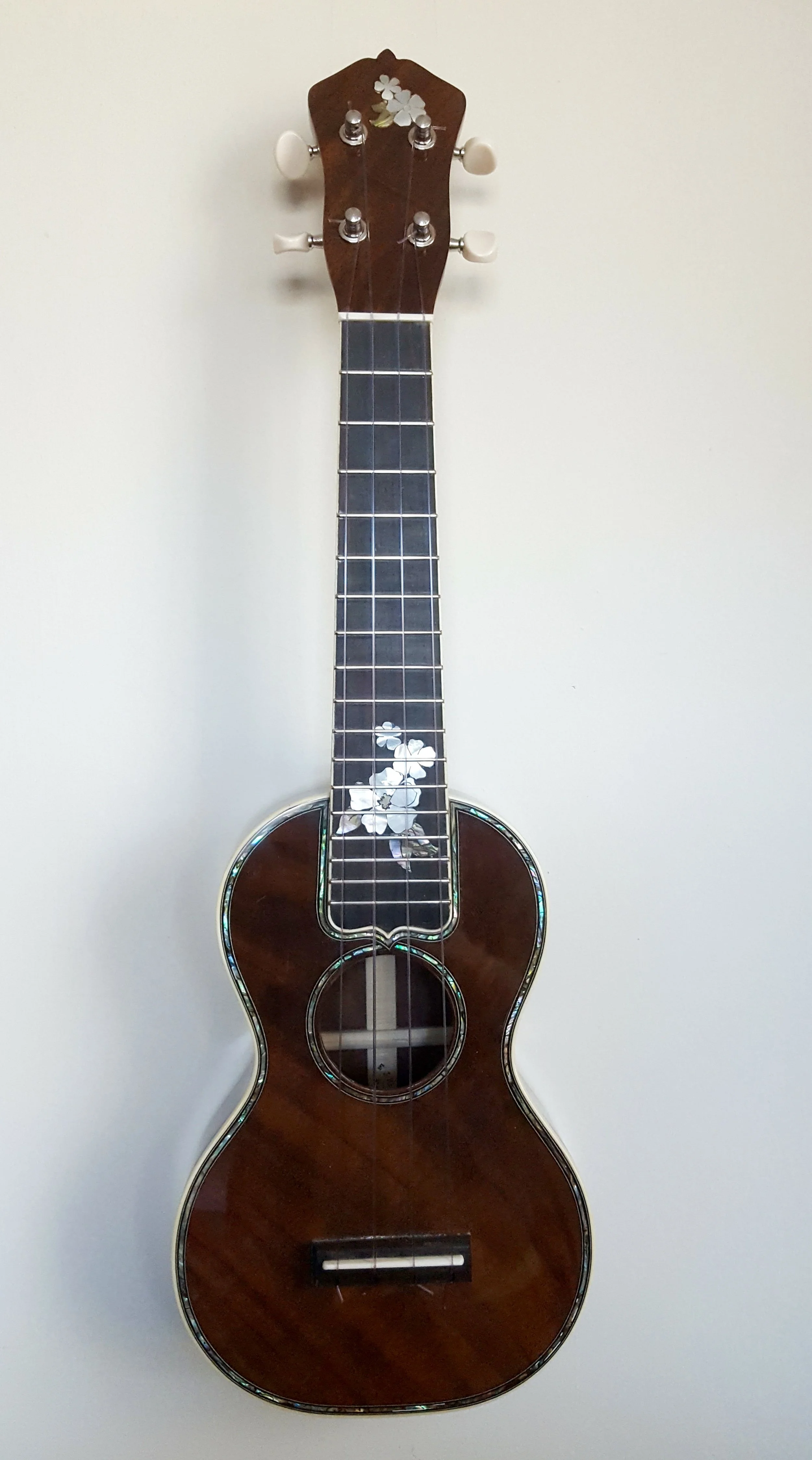 Soprano 42 style ukulele with custom flowers inlaid on the fingerboard and peghead. 