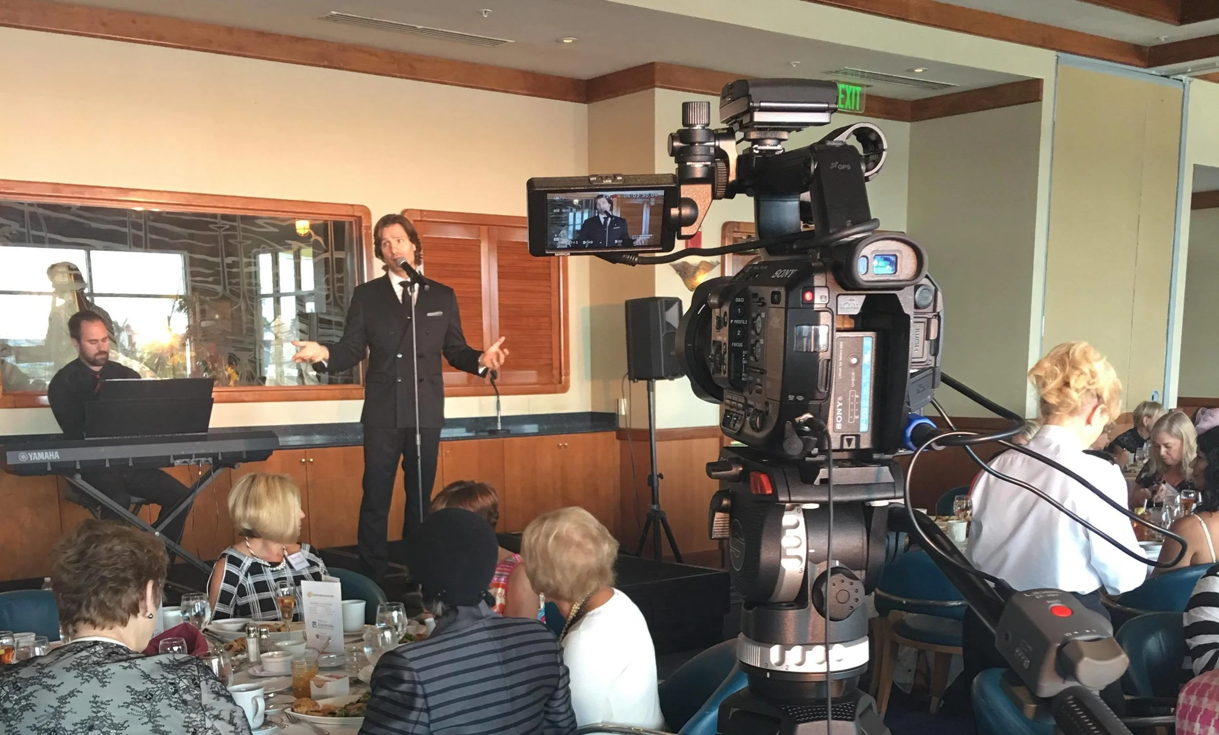 John Cudia singing on stage at the Naples Sailing & Yacht Club