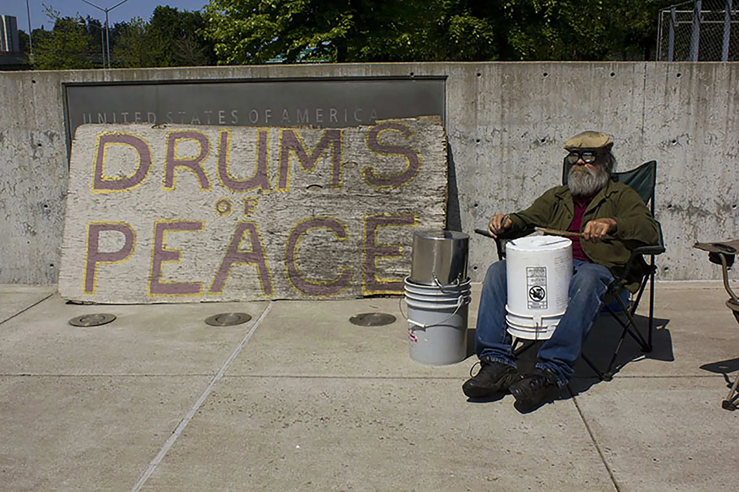  Jim Guthrie plays drums with his seven-year-old sign in front of the Eugene Federal Courthouse. 