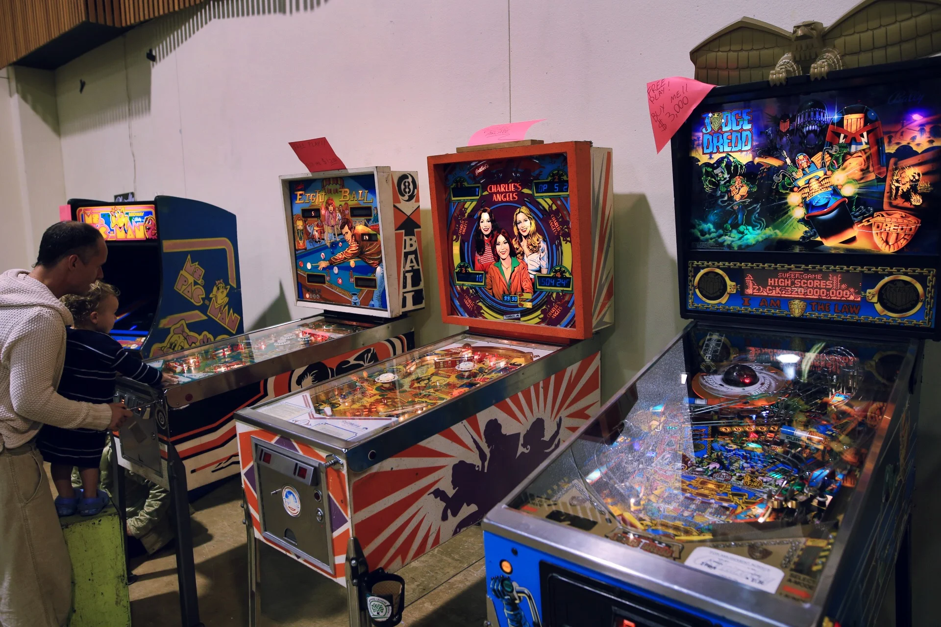  A father and son play on a vintage pinball machine.  