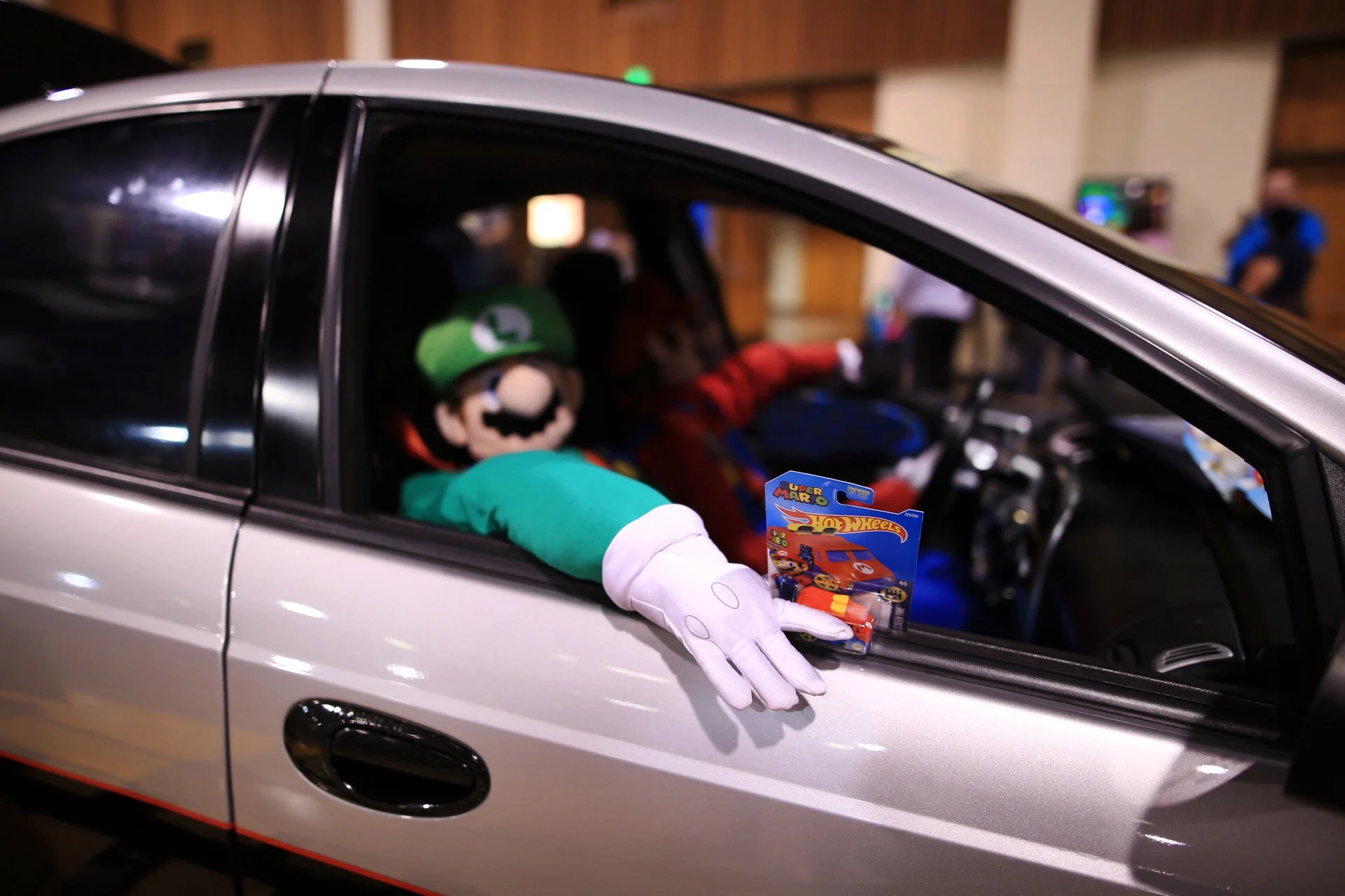  A life-size display of Mario and Luigi in a racing car, Hot Wheels in hand. 