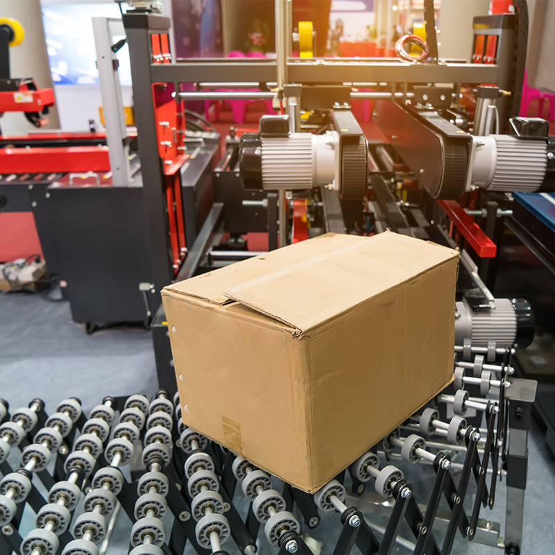 cardboard box being ran through black and red case sealing machine