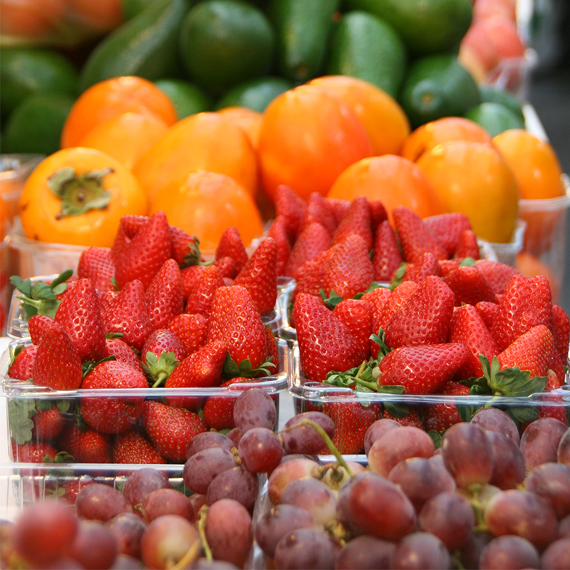 various fruits and vegetables packed in clear plastic trays in retail shelf for sale