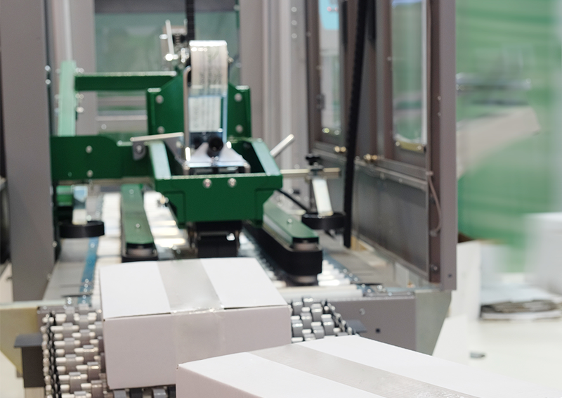 photo of an automatic case sealing system with a flexible conveyor moving white cardboard boxes
