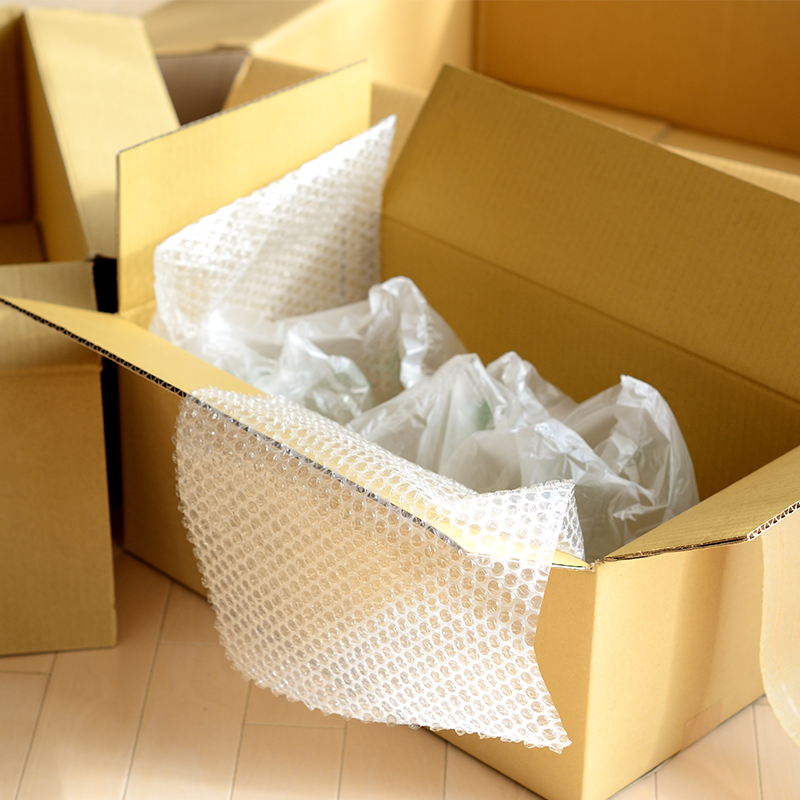 open cardboard box on floor filled with bubble wrap and air pillows