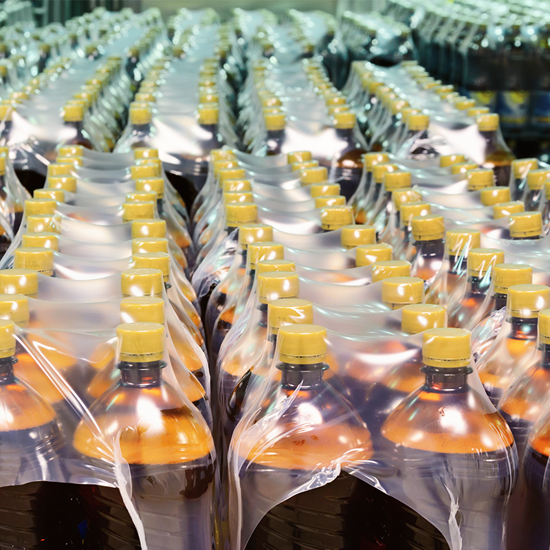 shrink wrapped packes of bottled pop in processing facility