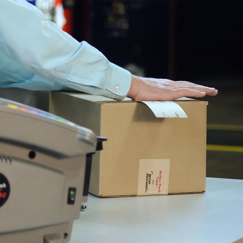 person sealing carton with printed water-activated tape and Better Pack 555e Automatic WAT Dispenser