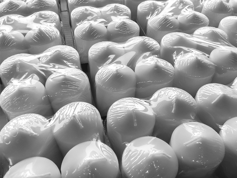 bundles of four white candles wrapped in clear shrink wrap film on conveyor system