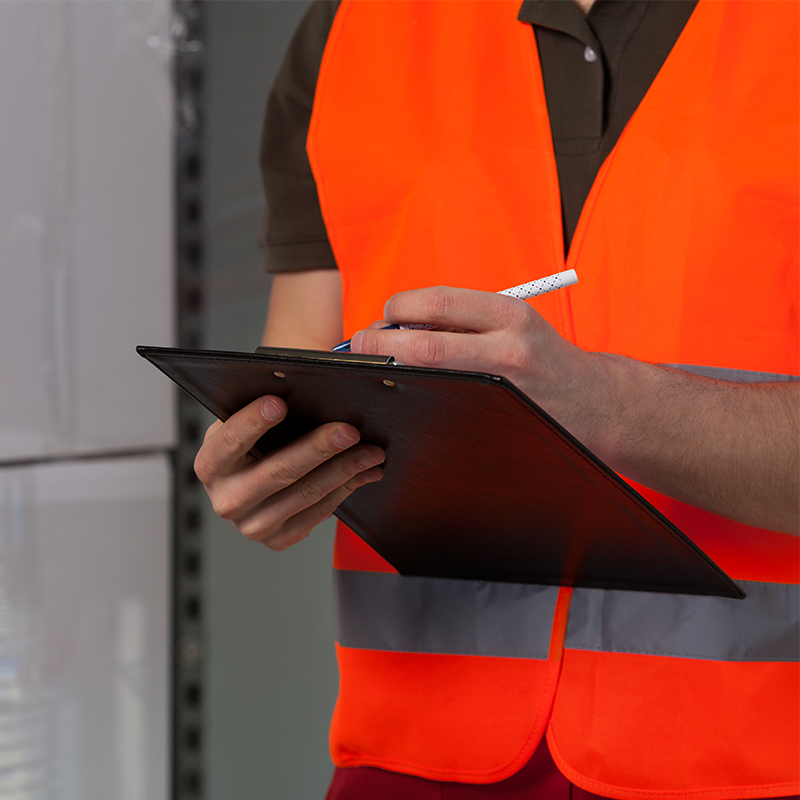 man holding clipboard next to stretch wrapped pallet
