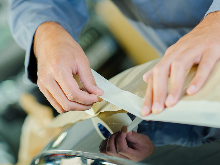 hands of a man placing masking tape on surface preparing for painting process