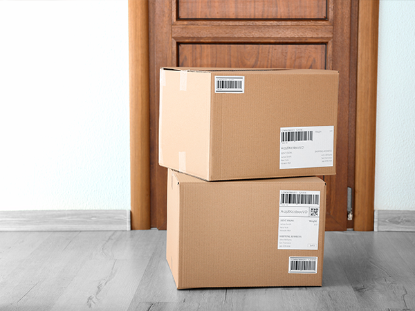 stack of two cardboard boxes on front door step of wooden door