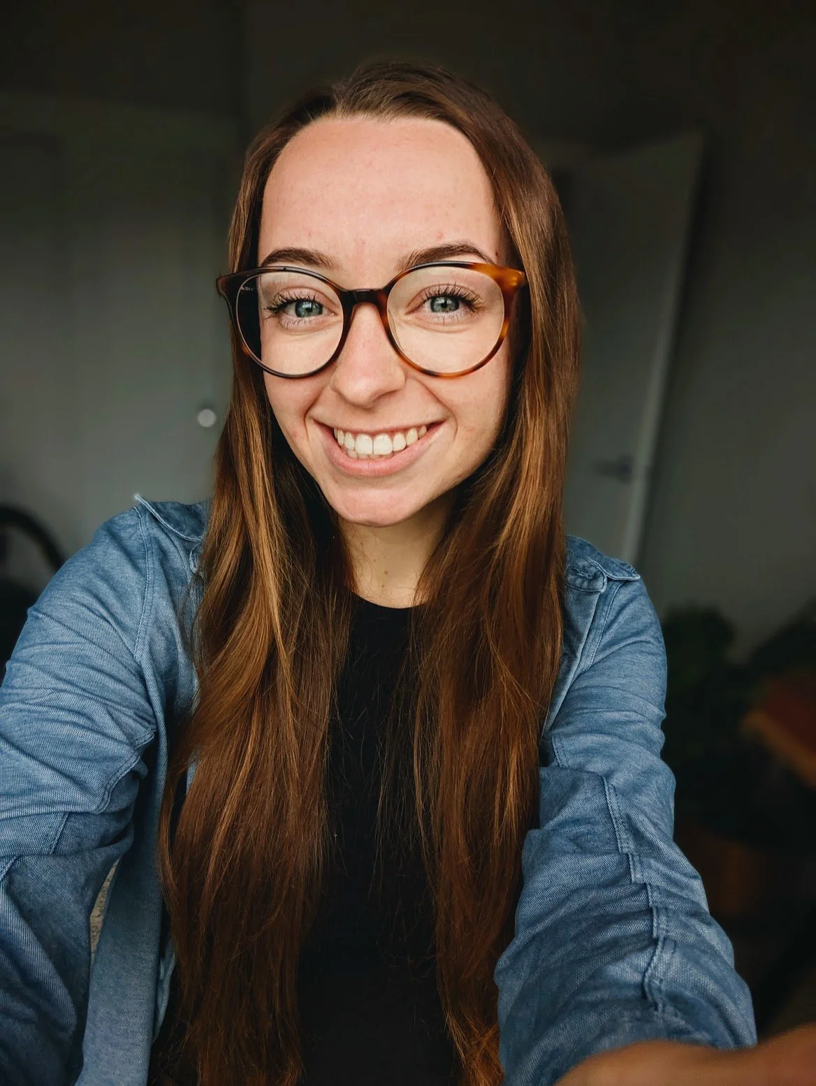Smiling person with long, wavy hair indoors.