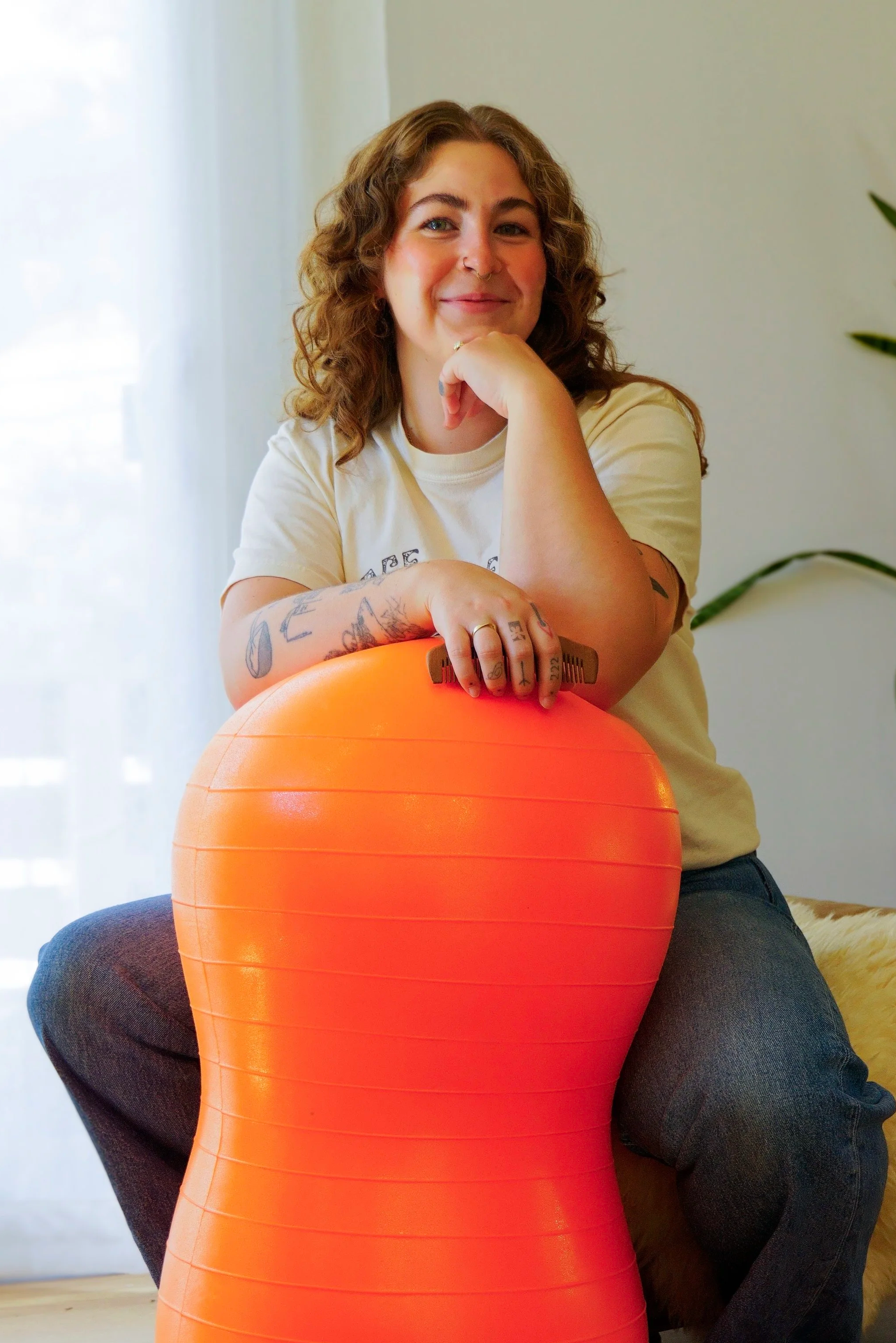 Woman with wavy hair sitting with an orange peanut ball.