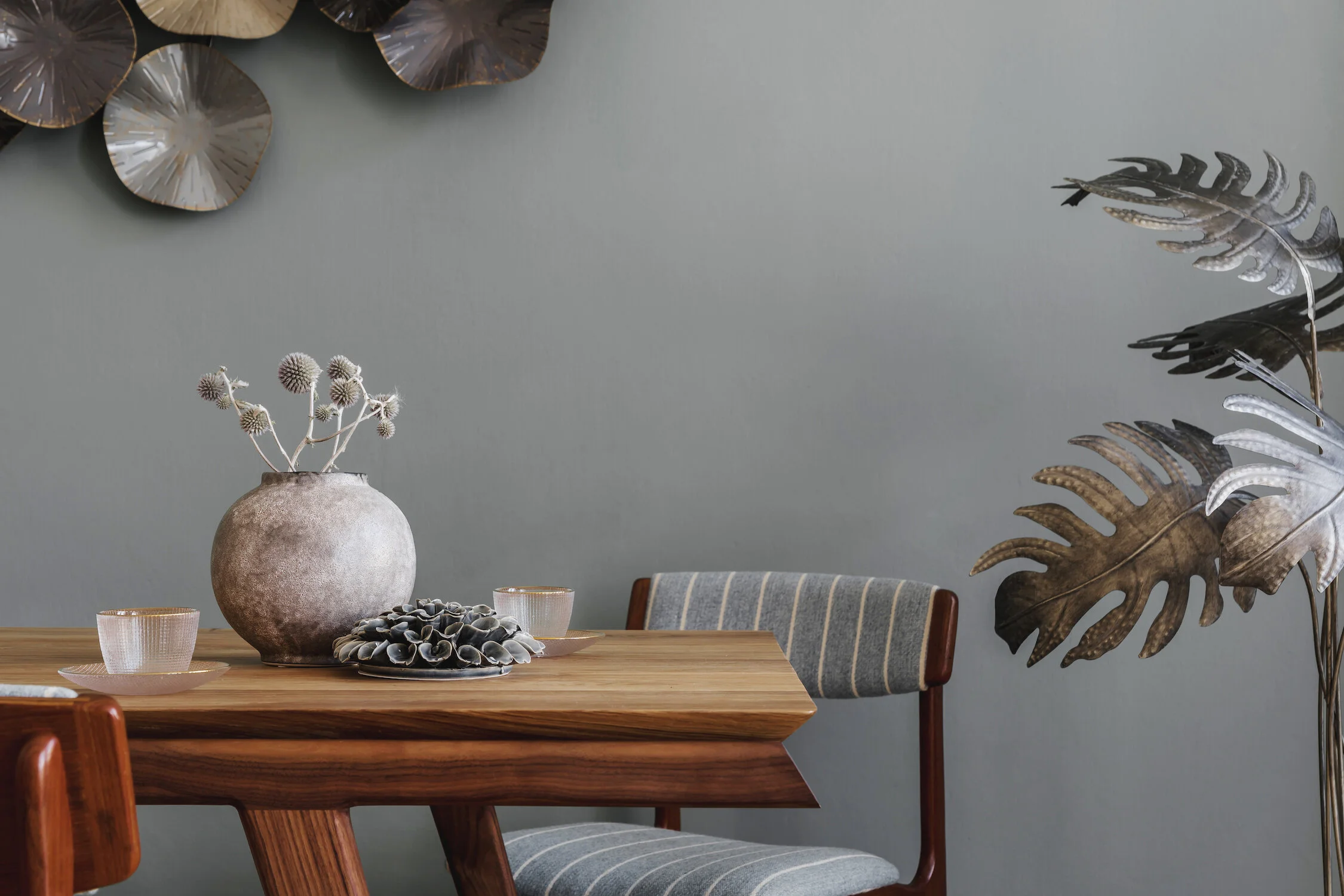 Modern and stylish dining room interior with glamour wooden table , elegant chairs and design decoration. Template. Home decor. Gray background wall.