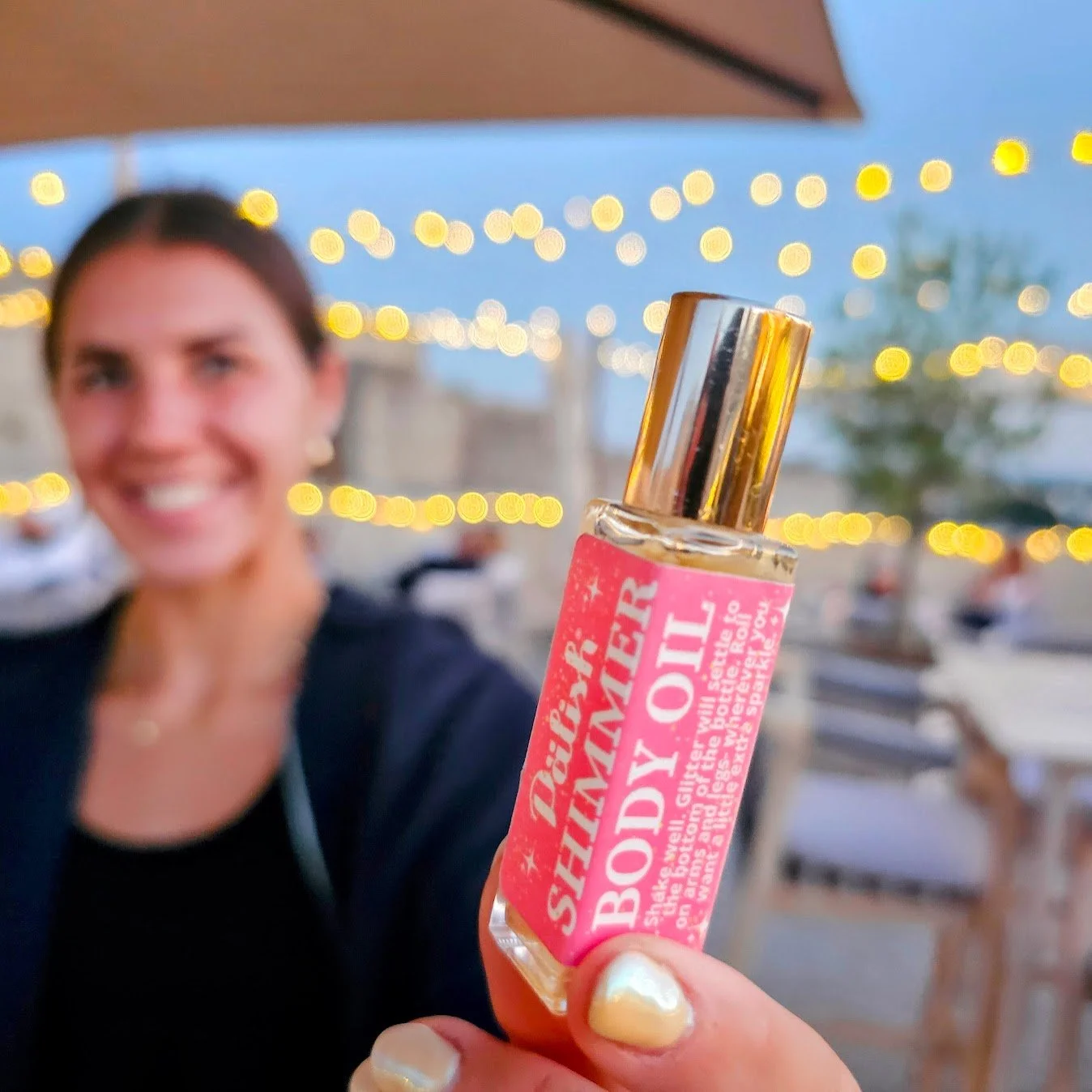Girl holding shimmer body oil roll-on in Caen France as a great way to have some sparkle to your night life travel ready made in ohio by palish.jpg