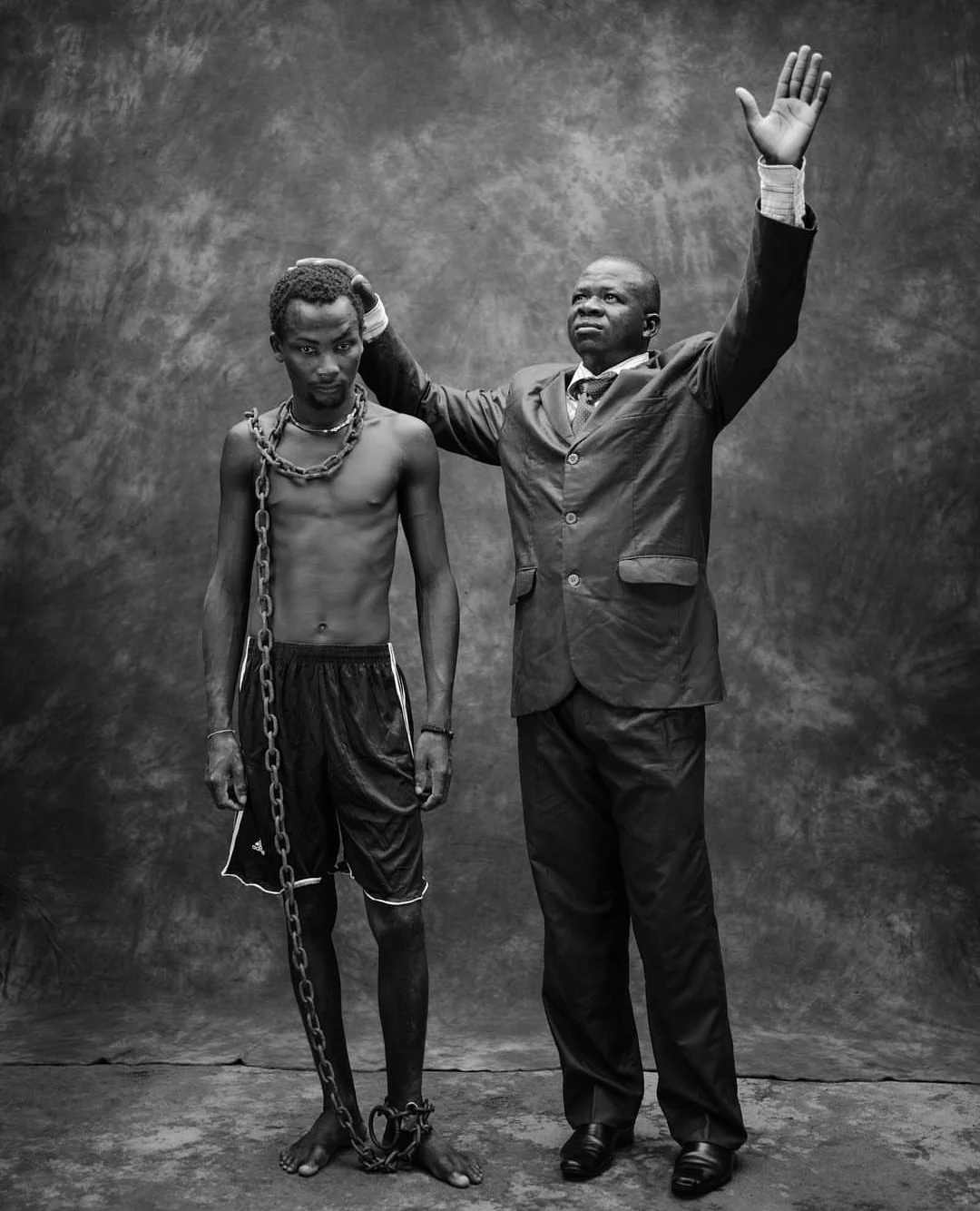 Togo: Pentacostal pastor Lare Damitote Bertrand with a chained, mentally ill man he claims to heal with prayer. Image: by Robin Hammond for National Geographic